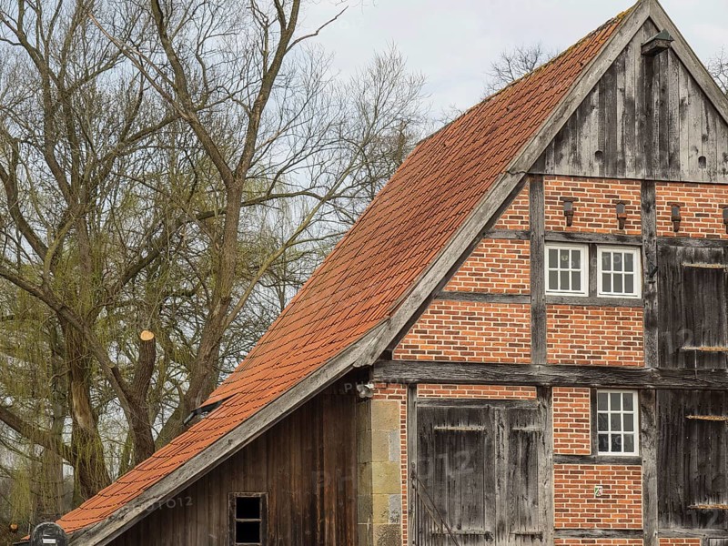 Half-timbered house with striking gable and red roof tiles. Rustic and old-fashioned building with trees in the background, heek, nienborg, münsterland, germany