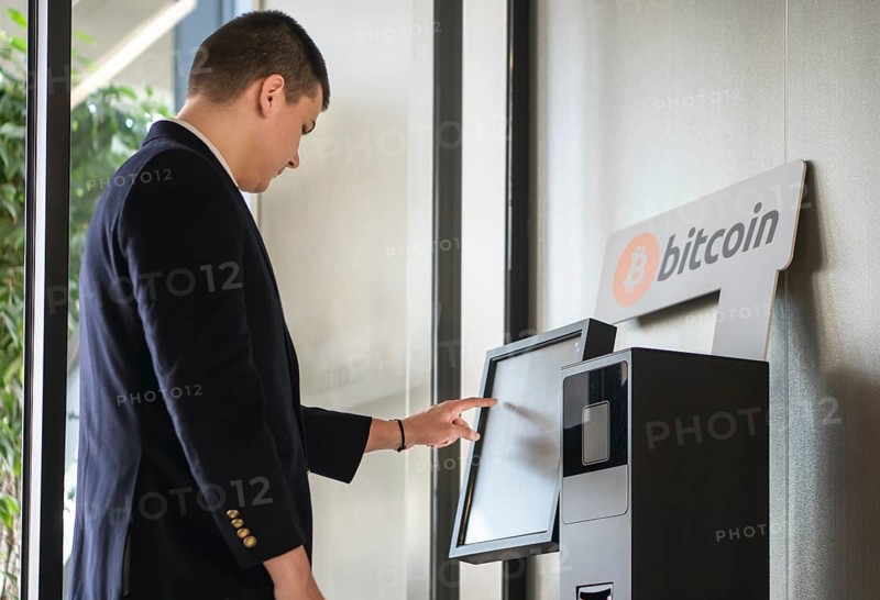 Young businessman buying cryptocurrency on ATM