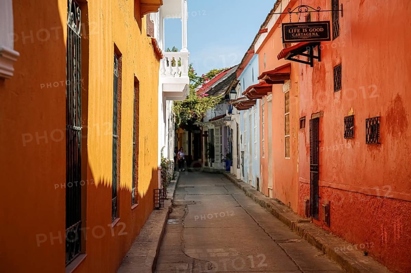 Narrow street in the old town of Cartagena with colorful one-story houses in sunlight and shadow, Colombia, South America