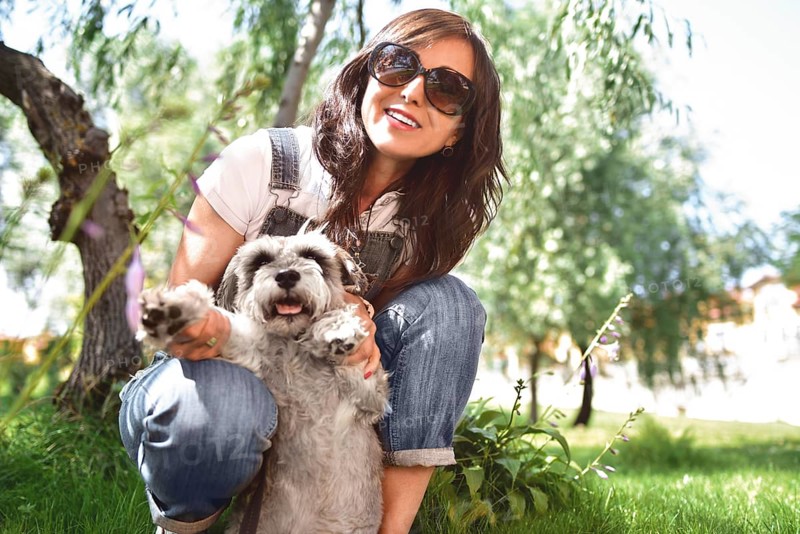Happy caucasian woman in sunglasses resting in nature with her beloved dog schnauzer