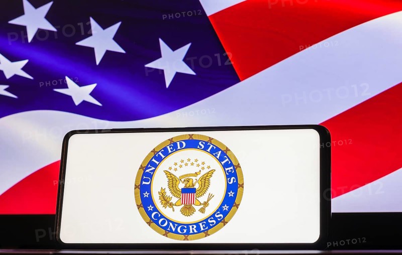 In this photo illustration the United States Congress logo seen displayed on a smartphone screen, United States of America flag in the background