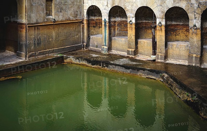 Water and buildings in an old roman bath in the city of Bath in the united kingdom england