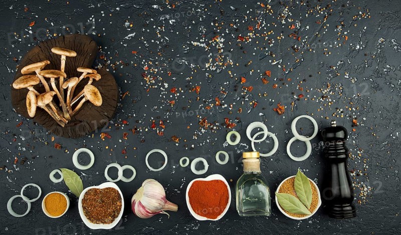 Fresh mushrooms with spices and herbs on black board. View from above. Copy space