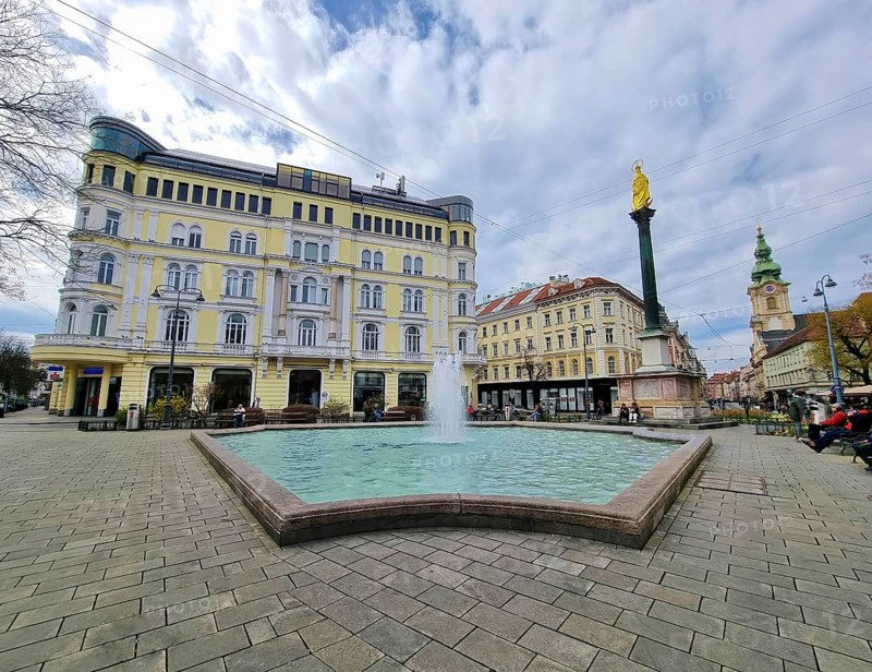 Graz, Austria - 26.03.2023: Mary's Column and fountain in Jakominiplatz Square and Parish Church in the background, famous attraction in the city center of Graz, Steiermark region, Austria, Europe