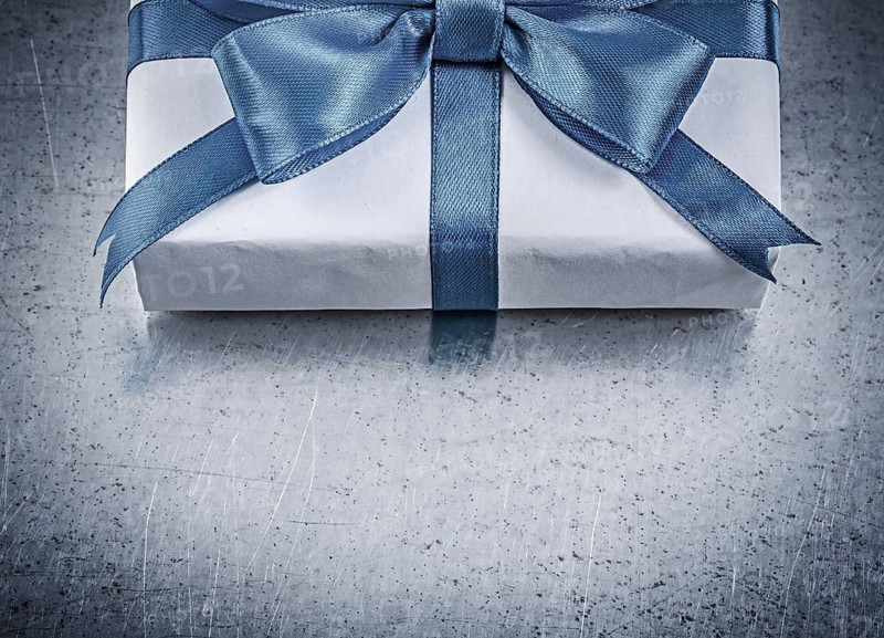 Present box with blue ribbon on metallic background celebrations concept