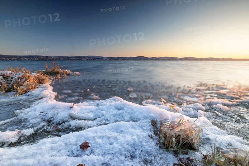 Snow-covered lakeshore with gentle waves at sunrise, Niederzell, Reichenau, Lake Constance, Baden-Württemberg, Germany, Europe
