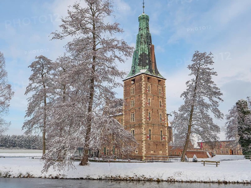 Historic castle tower on the lake in winter with snow-covered trees and a clear sky, Raesfeld, münsterland, germany