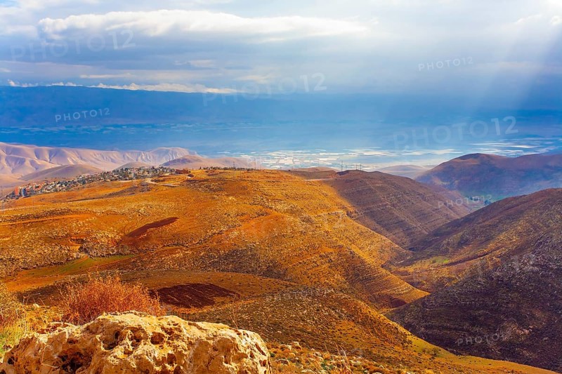 Legendary Dead Sea. Ancient terracotta-colored mountains surround the healing waters of the Dead Sea. The sun's rays illuminate the picturesque hills. Israel