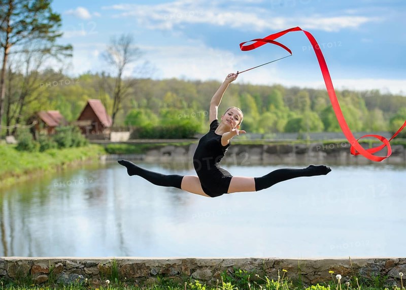 Young rhythmic gymnast doing split jump during ribbon exercises