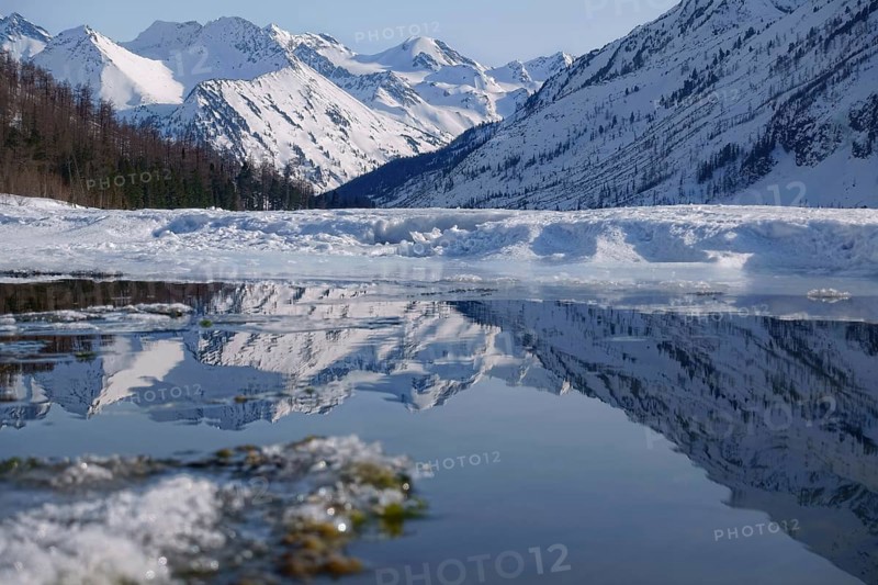 Winter landscape with mountain lake and high mountains reflected