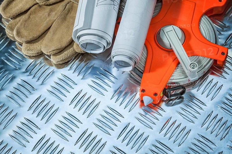 Protective gloves tape measure construction drawings on corrugated metal plate