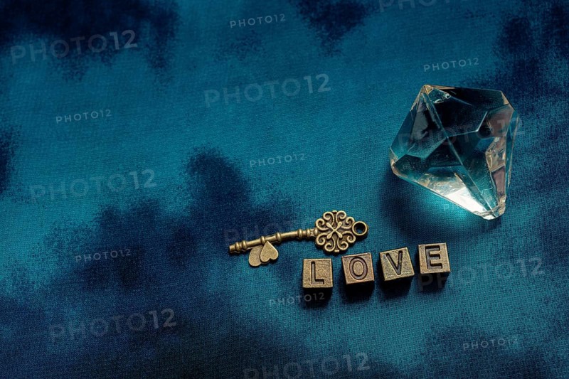 Ornamental key and fake diamond beside love wording with metal letters