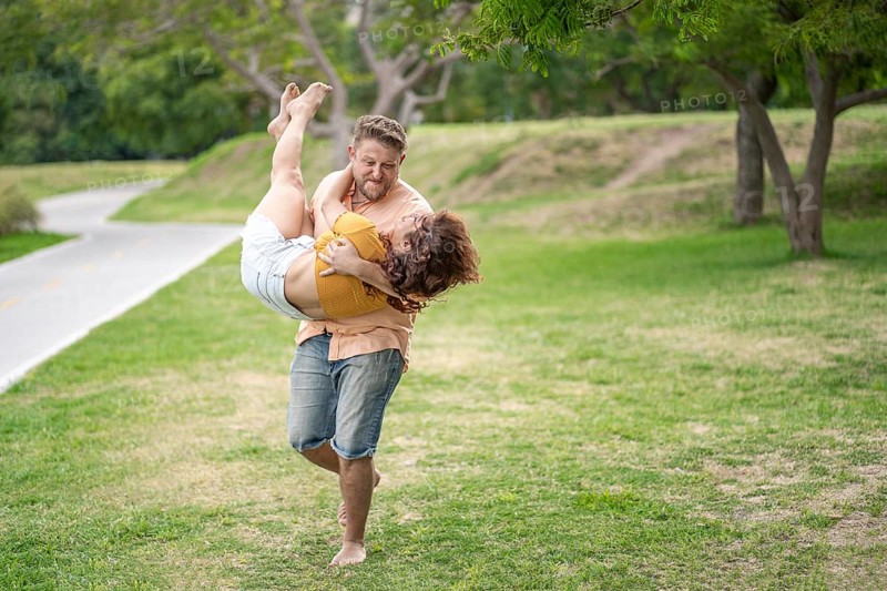 Man running in a park carrying his girlfriend in his arms