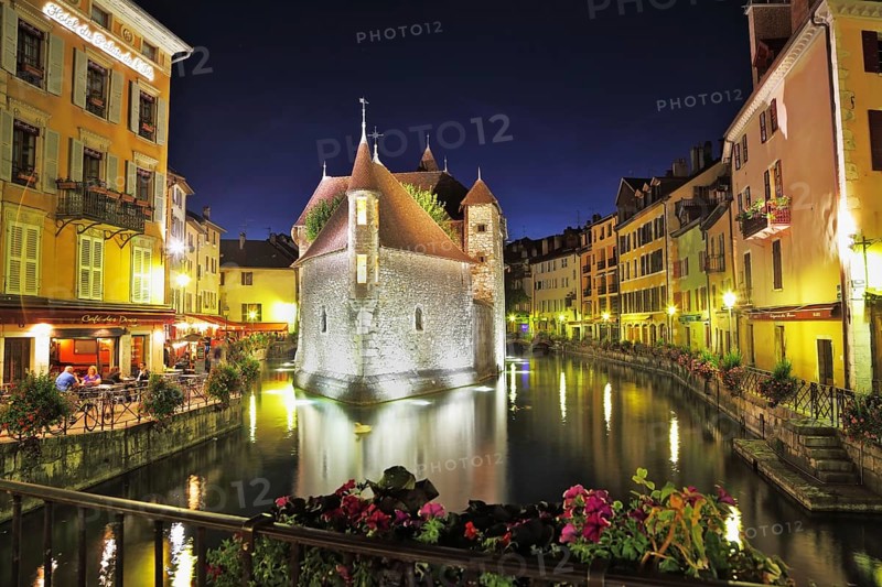Old fortress-prison on the island. Castle illuminated by spotlights and is beautifully reflected in the dark water. Summer night in the charming medieval town. Photo taken from the bridge