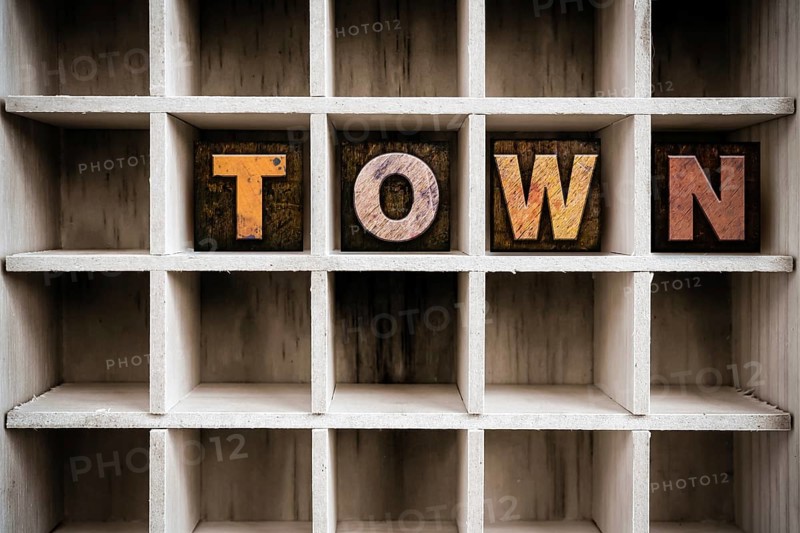 The word TOWN written in vintage ink stained wooden letterpress type in a partitioned printer's drawer