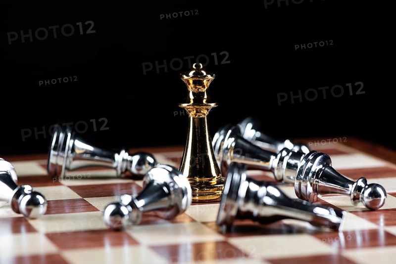 Gold queen chess defeats silver figures on wooden chessboard. Intellectual duel and tactical battle in business. Strategy planning, leadership and teamwork. Checkmate and winning in game concept