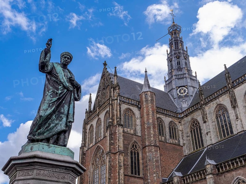 Monument to the Dutch inventor of letterpress printing Laurens Janszoon Coster on the Grote Markt and in the background the St. Bavo Cathedral (De Grote of St. Bavokerk te Haarlem) in the centre of the old town, Haarlem, North Holland, Netherlands