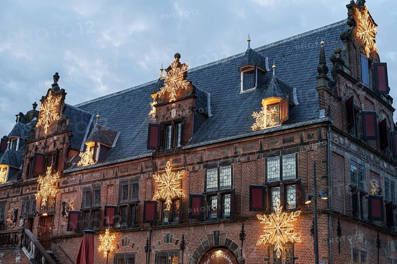 Old building with Christmas decorations and stars on the roof under a cloudy sky, nijmegen, the netherlands