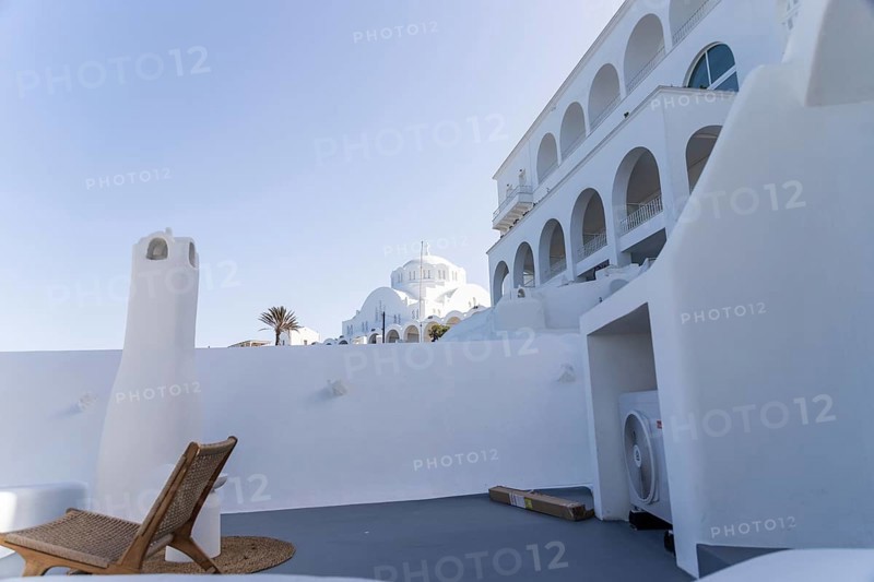 Deckchair on a viewpoint of a hotel complex, white buildings, orthodox cathedral in the background, Fira, Santorini island, Greece, Europe