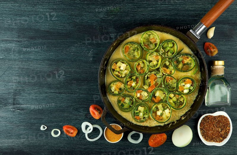 Zucchini in the background. Fried young sliced courgettes in a pan on a dark background. The view from the top. Copy space