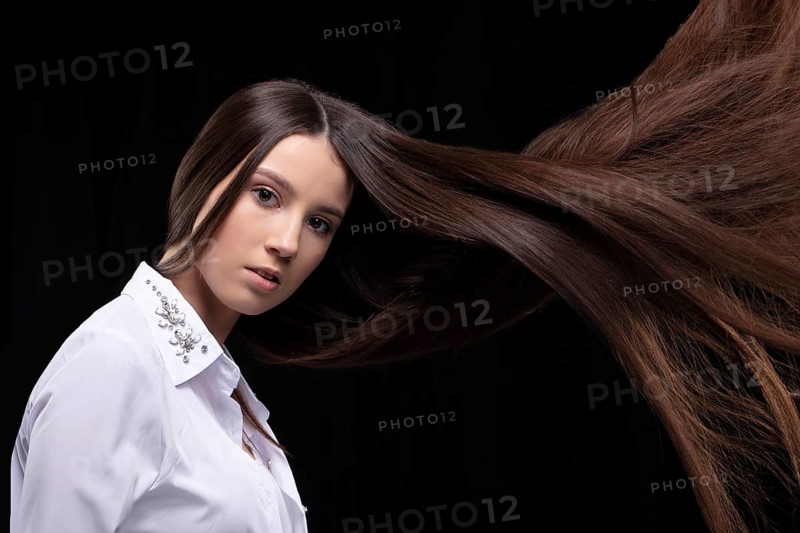 Beautiful brunette with long flying hair on a dark background
