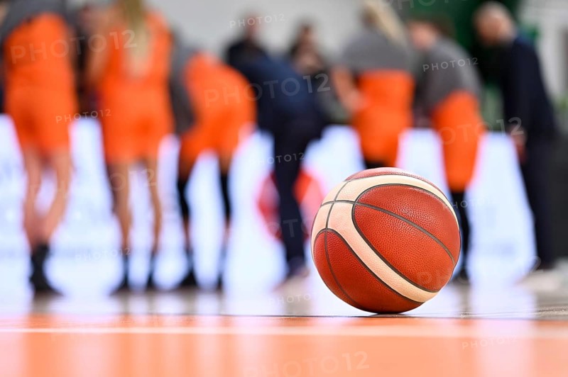 The ball lying on the parquet and the basketball team in the background.