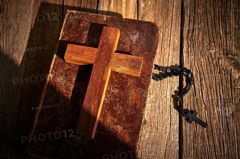 Christian cross on wood bible and rosary beads over wooden vintage background