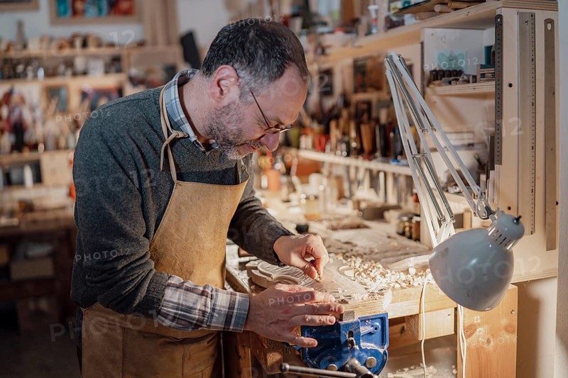 A craftsman meticulously shaping a violin part, surrounded by woodworking tools