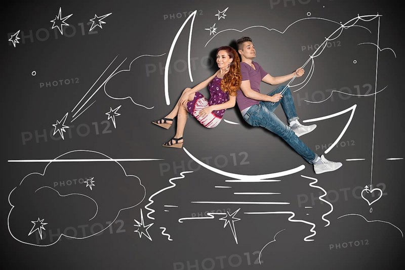Happy valentines love story concept of a romantic couple fishing on a moon with a heart on a hook against chalk drawings background
