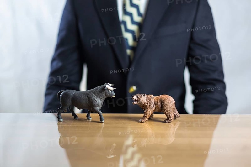 Stock market, securities trading and capitalism concept with a bull and bear concepts. Business trader man in suit in background