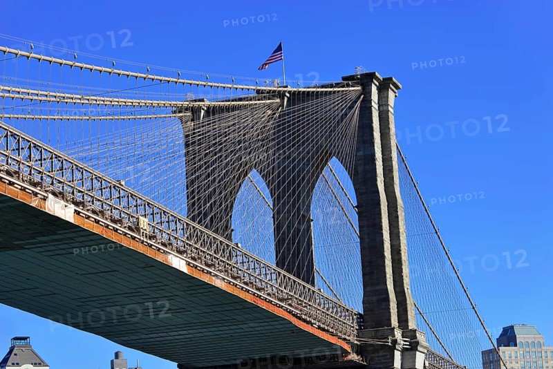 Brooklyn Bridge in Brooklyn, Manhattan, New York, section of a bridge with waving American flag and clear blue sky, New York City, USA, North America