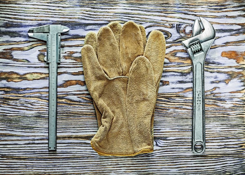 Vernier caliper adjustable spanner safety gloves on wooden board