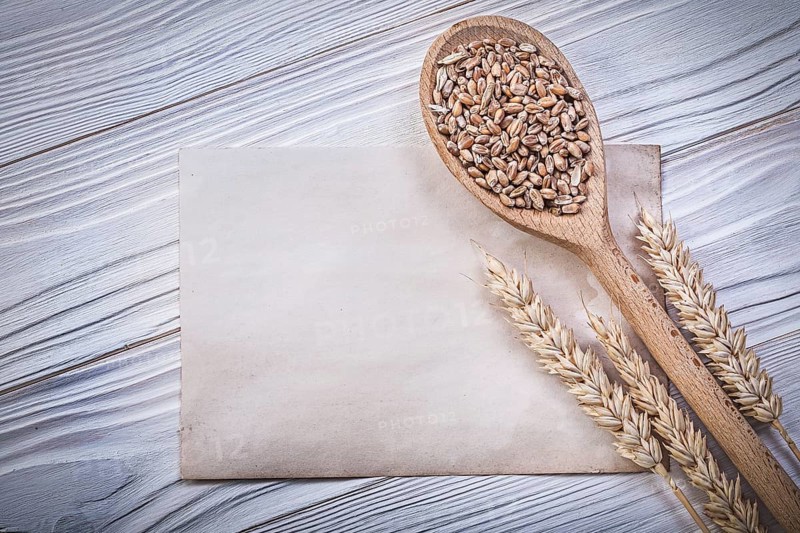 Ripe wheat rye ears grain wooden spoon clean vintage paper sheet on wood board top view