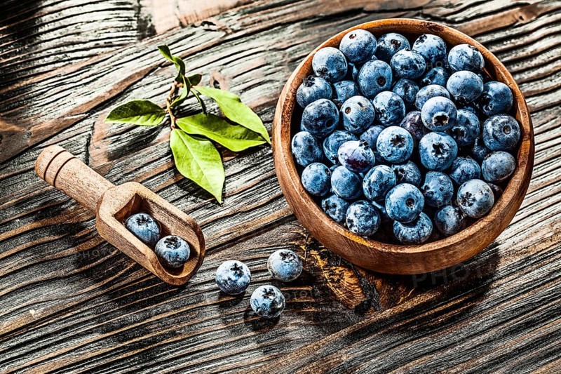 Raw huckleberries in wooden spoon bowl