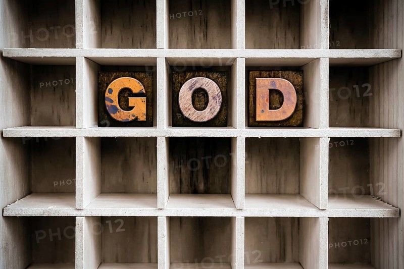 The word GOD written in vintage ink stained wooden letterpress type in a partitioned printer's drawer