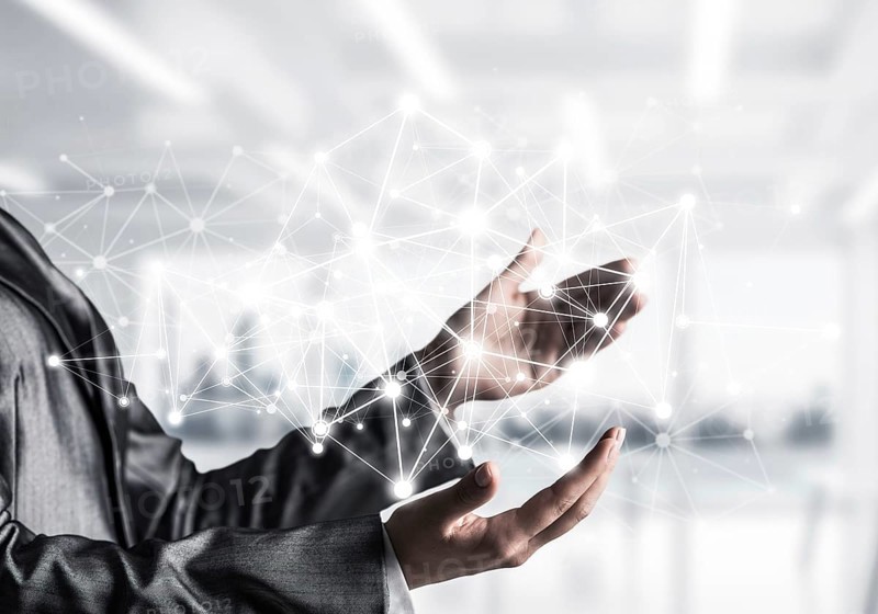 Business woman in suit keeping white social media network structure in hands with office view on background. Mixed media