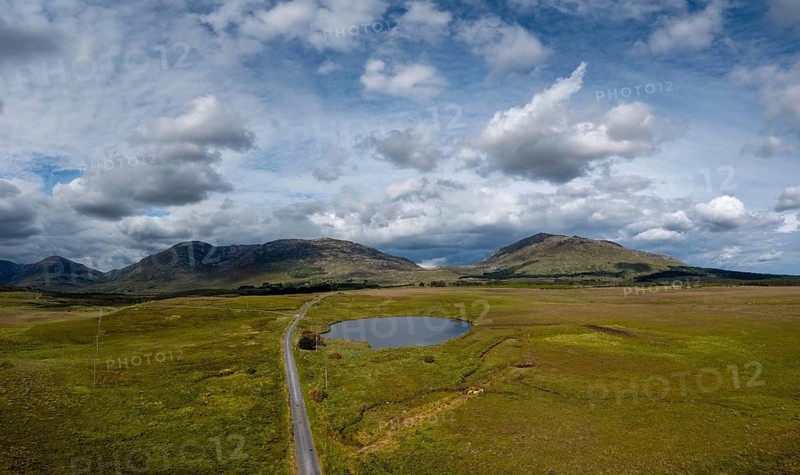 Narrow country road leads into the wild landscape of the Connemara National Park in western Ireland