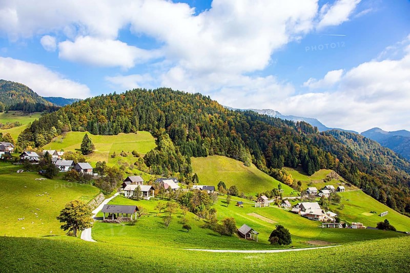 Small village in mountain valley. Picturesque Julian Alps. Beautiful autumn day. Charming pastoral. Green grassy lawns in a mountain valley. Travel to Slovenia
