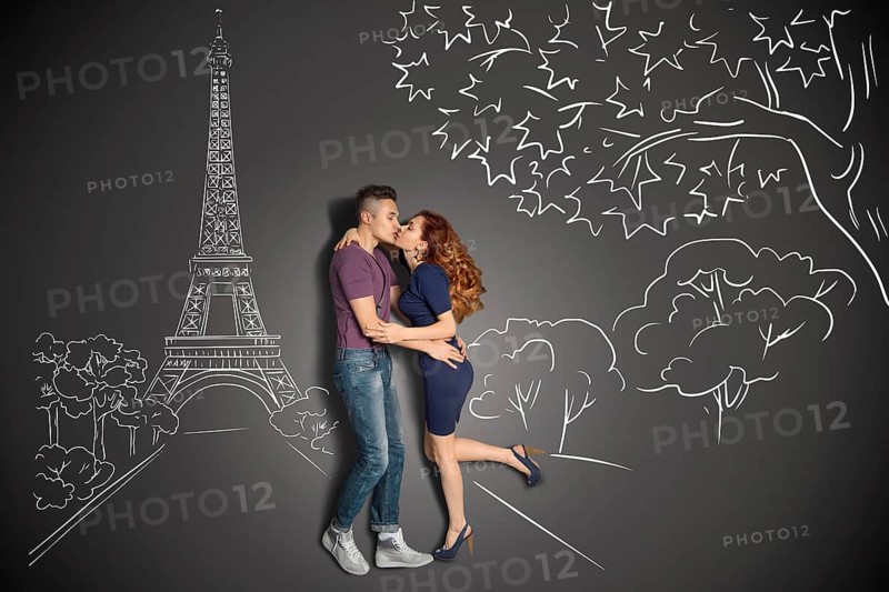 Happy valentines love story concept of a romantic couple in Paris kissing under the Eiffel Tower against chalk drawings background