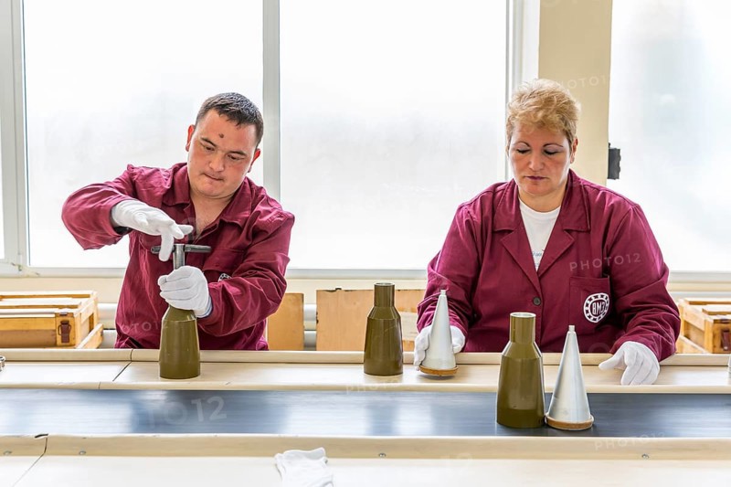 Sopot, Bulgaria - May 17, 2016: Workers are tightening explosive elements of anti-tank rocket-propelled grenades (RPG, bazooka) at an assembly line in a munition factory. Working with white gloves
