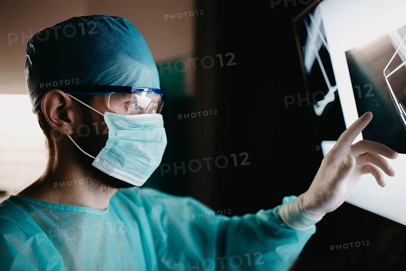Doctor analyzing x-ray images with focused attention and protective gear