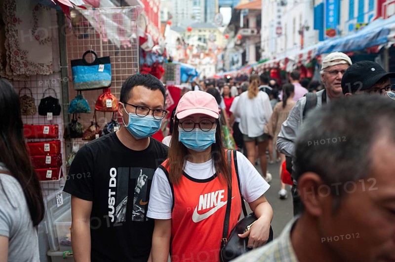 24.01.2020, Singapore, Republic of Singapore, Asia, Pedestrians wearing face masks stroll through a busy street bazaar in the Chinatown district, which takes place every year for Chinese New Year. This comes shortly after the first coronavirus infection was confirmed in the city-state, Asia