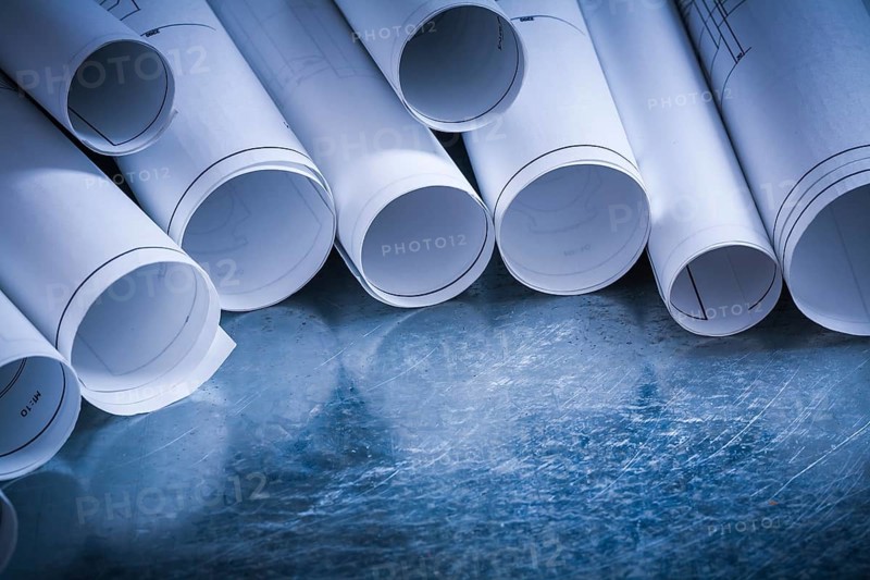 Set of rolled up white construction drawings on scratched silver-metal surface building and architecture concept