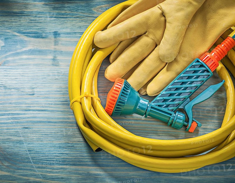 Leather protective gloves garden hose on wooden board gardening concept