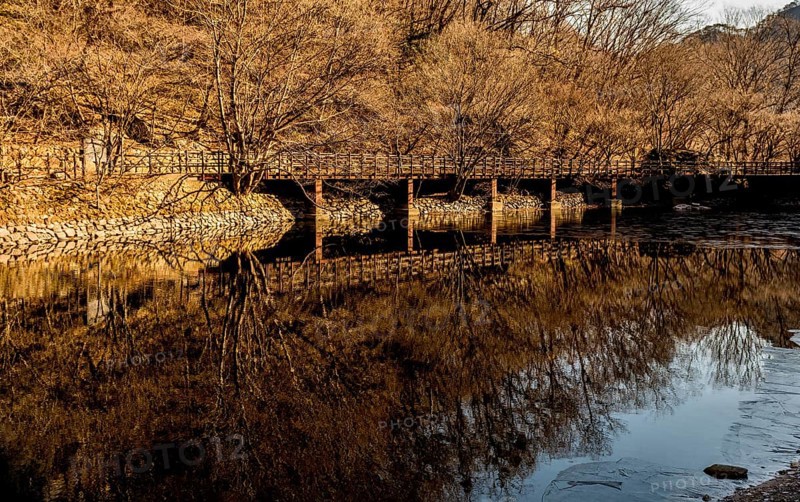 Jeongeup-si, South Korea. December 8, 2020: Winter landscape of bridge reflecting in water of shallow river on sunny morning