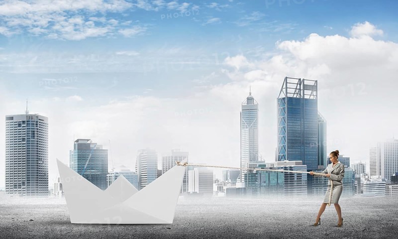 Successful businesswoman pulling with rope paper boat