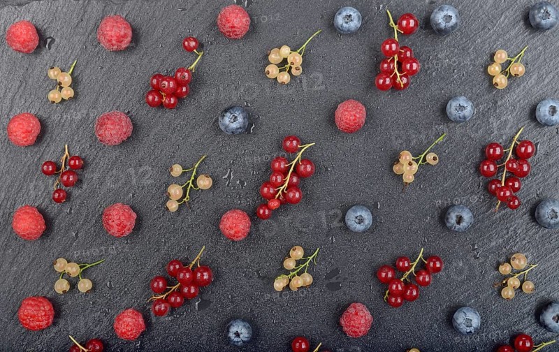 Flat lay view at ripe bilberry raspberry white and red currant on slate stone tray closeup