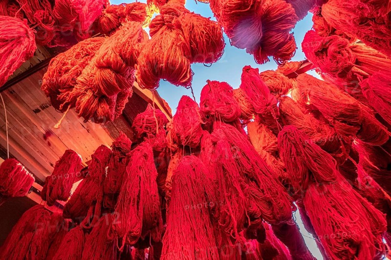 Red colored threads of fabric hanging to dry for sale in a souk in Marrakesh Morocco