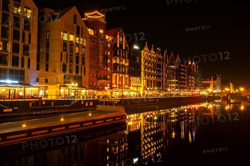 Old town in Gdansk at night. The riverside on Granary Island reflection in Moltawa River Cityscape at twilight. Ancient crane at dusk. Visit Gdansk Poland Travel destination. Tourist attraction