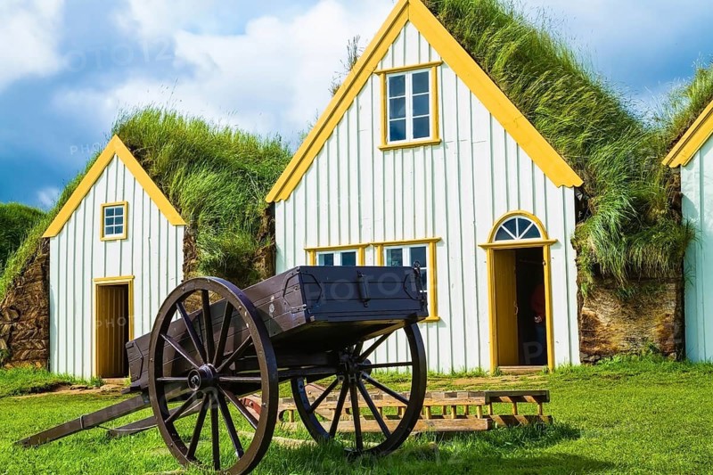 The ancient two-wheeled wooden cart on the front lawn. The village first settlers in Iceland. The reconstituted village - Pioneer Museum - Viking
